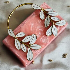 Pink resin clutch with leaves embellishments and a golden handle. 🥰